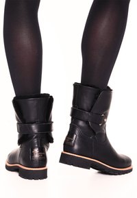 Black leather ankle boots with a rounded toe, fur lining at the top, and a side buckle detail; rugged sole for traction.
