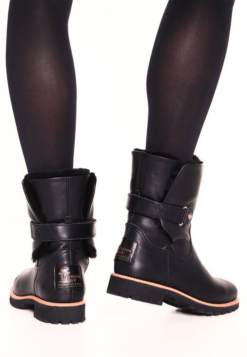 Black leather ankle boots with a rounded toe, fur lining at the top, and a side buckle detail; rugged sole for traction.