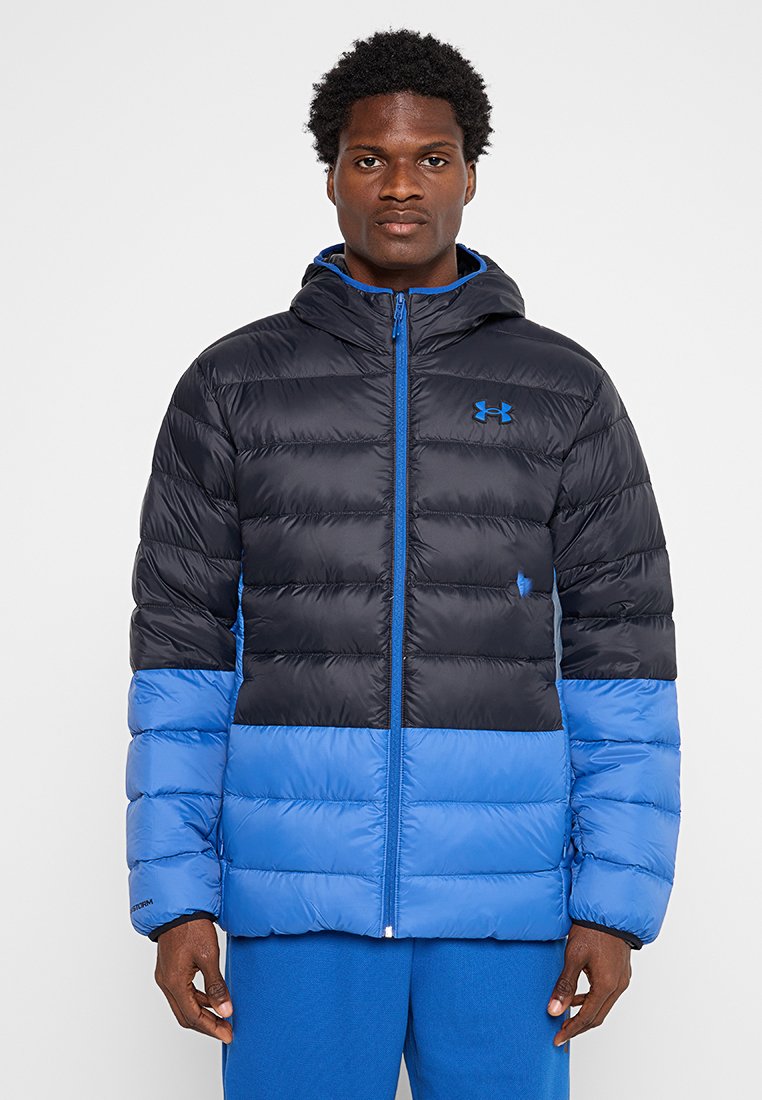 Doudoune noire et bleue avec capuche, fermeture éclair, design matelassé, et empiècements de couleur contrastante au bas et aux manches.