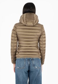 Giacca imbottita marrone, trapuntata e con cappuccio, dal design aderente e cuciture orizzontali, abbinata a jeans in denim azzurro chiaro.