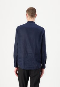 Camicia a maniche lunghe blu navy in un tessuto leggero, con colletto classico e polsini abbottonati. Tessuto liscio con vestibilità rilassata.