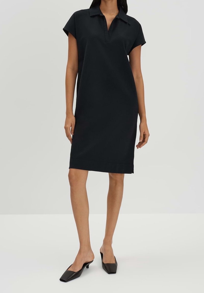 Czarna sukienka polo z kołnierzykiem, krótkimi rękawami i prostym krojem, wykonana z gładkiego materiału, sięgająca tuż nad kolano.
