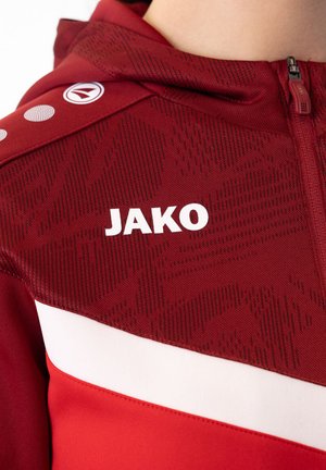 Rode sportieve jas van gestructureerd materiaal met een capuchon, wit "JAKO" logo en een horizontale witte streep over de borst.