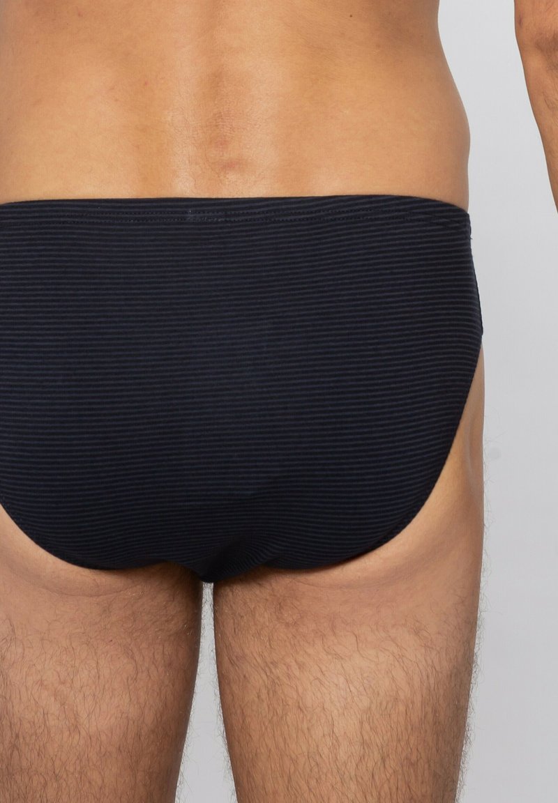 Svarta simbrallor med ett horisontellt randmönster, med en låg sittande design och mjukt tyg som formas efter kroppen.