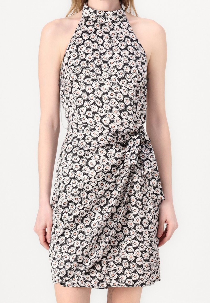 Robe sans manches à col halter, fond noir avec motif floral de marguerites blanches, avec un détail noué à la taille et une longueur au-dessus du genou.