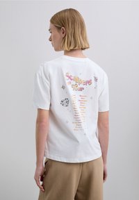 White cotton t-shirt featuring "Scalpers Tour" text in colorful designs on the back, with stars and a heart graphic. Relaxed fit, crew neck.