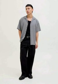 Short-sleeve, collared shirt in gray textured fabric, buttoned, paired with black wide-leg pants and black shoes. Simple, modern design.