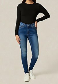 Wąskie dżinsy w średnim niebieskim odcieniu, wysoki stan z wyblakłymi akcentami. W połączeniu z dopasowanym czarnym długim rękawem i białymi sneakersami.