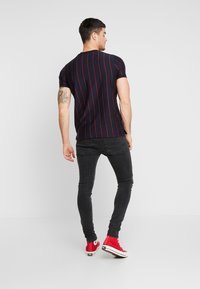 Μπλάζα ναυτικού τύπου με ρίγες κόκκινες, κοντά μανίκια, εφαρμοστή γραμμή. Συνδυασμένη με μαύρα skinny τζιν και κόκκινες ψηλές αθλητικές παπούτσια.