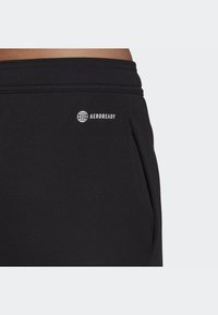 Black athletic shorts made of soft fabric, featuring an AEROREADY logo and side pockets, with a smooth texture and elastic waistband.