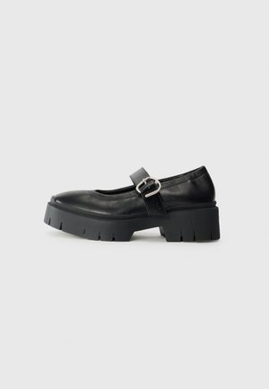 Svarte lær Mary Jane-sko med en chunky plattformsåle, rund tå og side-spenne detalj. Glatt tekstur med minimal søm.