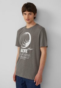 Grijze katoenen t-shirt met een ronde afbeelding van een surfer, vetgedrukte tekst "PACIFIC CALIFORNIA" en een ontspannen pasvorm.