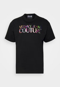 Černé tričko s krátkým rukávem se barevným nápisem "Versace Jeans Couture" tištěným na hrudi.