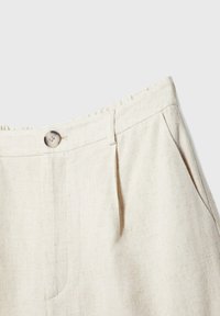 Pantalon en lin beige à texture lisse, avec une fermeture avant par bouton, des plis et des poches latérales.