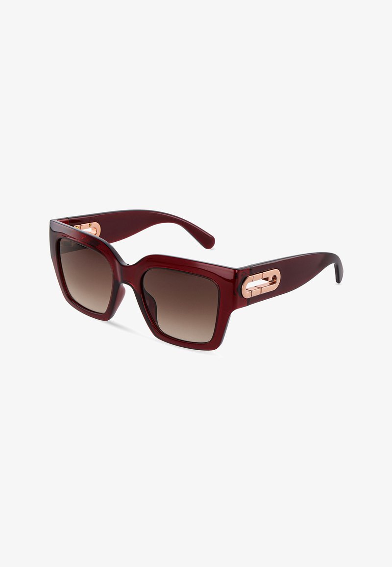 Lunettes de soleil carrées oversize rouge foncé avec verres marron dégradés et accents dorés sur les charnières des branches, sur fond blanc.