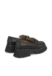 Schwarze Leder-Plateau-Loafer mit einer dicken, robusten Sohle. Mit Metallbeschlägen und Nietenverzierungen entlang des Sohlenrands.