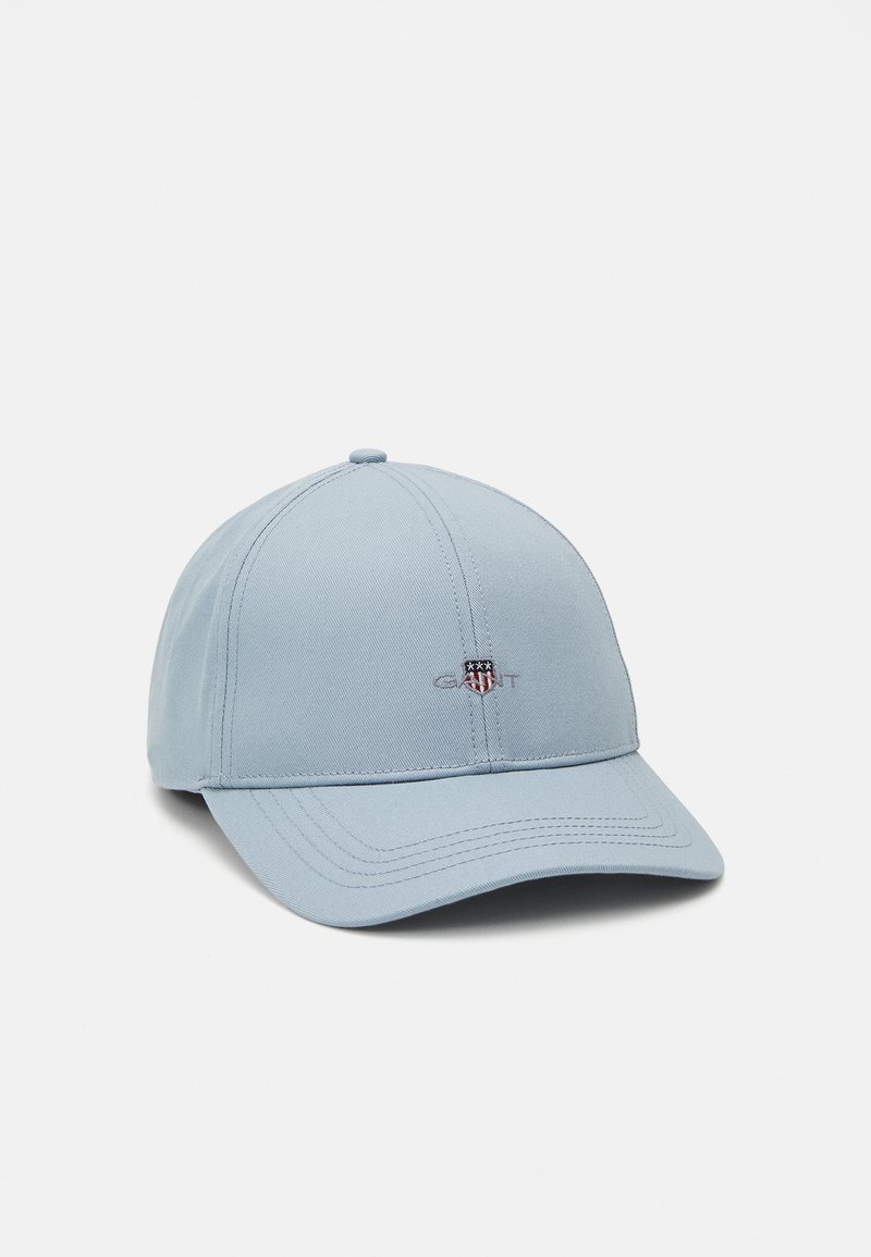 Lyseblå baseballcap laget av stoff med seks paneler, en buet skjerm og brodert logo på forsiden. Justerbar stropp bak.