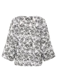 Blouse blanche avec un motif floral noir, coupe ample, ourlet court et manches larges 3/4. Le tissu a une texture lisse.