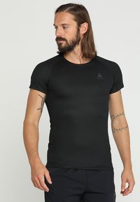 Black short-sleeve athletic shirt made of breathable fabric with a textured pattern and a fitted silhouette. Logo on upper left chest.