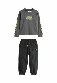 Dunkelgrauer Langarmpullover mit gelbem "Baker by Ted Baker"-Text und schwarzen Hosen mit elastischen Bündchen, Kordelzugbund und vorderen Taschen.
