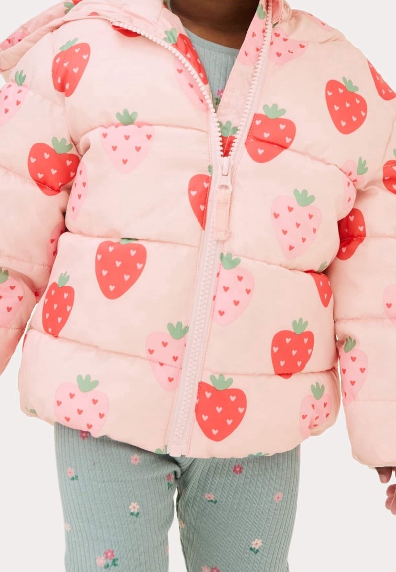 Roze pufferjack met een aardbeienpatroon, ritsluiting en een capuchon. Draagt over groene geribbelde leggings met bloemdecoraties.