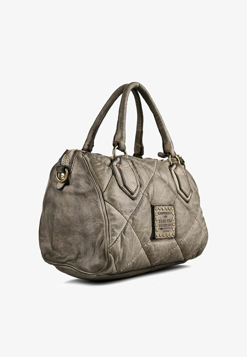 Sac à main en cuir matelassé gris avec deux poignées et une plaque métallique de la marque sur le côté décorée de rivets et de texte.