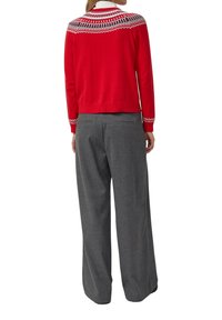 Czerwony dziergany kardigan z białym wzorzystym kołnierzem, zestawiony ze szarymi spodniami o szerokich nogawkach. Posiada ściągacze na mankietach i teksturowaną tkaninę.