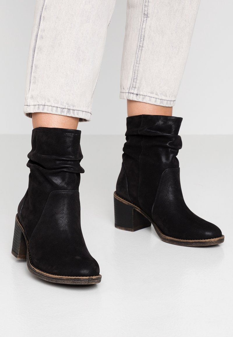 Botines negros de cuero con un diseño arrugado, que presentan una puntera redonda, tacón cuadrado y acentos texturizados en contraste.