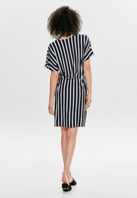 Vestido riscado em azul-marinho e creme, com mangas curtas, ajustado na cintura, acima do joelho, tecido leve, com detalhes em cor sólida nas mangas.