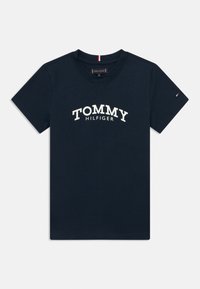 Camiseta de manga curta azul-marinho com o texto "TOMMY HILFIGER" na parte da frente e uma pequena bandeira da marca na manga direita.