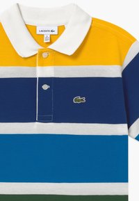 Polo Lacoste con rayas horizontales en amarillo, blanco, azul y verde. Diseño con cuello, dos botones y detalle de logo bordado.