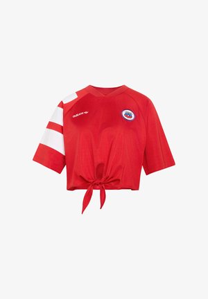 Maglia sportiva rossa corta con righe bianche sulla manica sinistra, logo Adidas, stemma della squadra del Cile e dettaglio con laccio frontale.