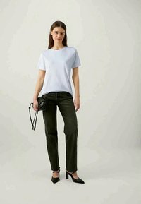 Light blue cotton t-shirt paired with dark green high-waisted jeans, accessorized with a small black crossbody bag and black heels.