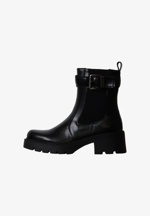 Bottine noire en cuir avec talon épais, panneau élastique latéral, bride réglable avec boucle et languette à l’arrière.