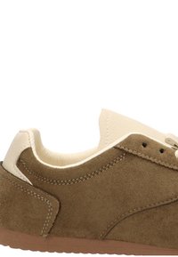 Zapatilla de suede marrón con un cuello de cuero beige, punta redonda y suela de goma texturada. Presenta detalles de costura y recortes laterales.