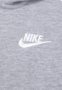 Ljusgrå hoodie med en vit broderad "Nike"-logotyp och en swoosh-design framtill. Mjuk textur med en minimalistisk design.