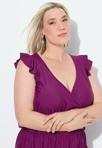 Fioletowa sukienka o kopertowym kroju z falbaniastymi rękawami, uszyta z gładkiego, elastycznego materiału. Posiada głęboki dekolt w serek i elastyczną talię dla komfortu.