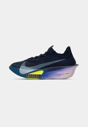 Scarpa da running Nike di colore blu scuro con grande swoosh argento, dettaglio giallo neon sulla suola e tallone imbottito spesso con una sfumatura dal viola al rosa.