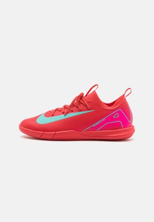 Raudoni sportiniai bateliai su struktūruota viršutine dalimi, turintys turkio spalvos swoosh logotipą, šoninius akcentus ir rožinį kulno detalę. Įtrauktos surištos raišteliai ir traukimo kilpa.