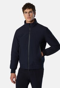 Veste zippée bleu marine avec col montant, dotée de poches latérales et de poignets côtelés, fabriquée dans un tissu lisse et résistant.