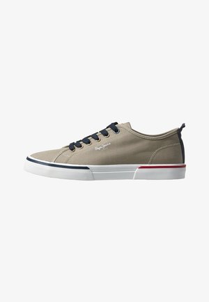 Zapatilla de lona beige de caña baja con cordones negros, suela blanca con detalles en azul marino y rojo, y logo de "Pepe Jeans" en el lateral.