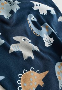 Tissu bleu marine avec des illustrations ludiques de dinosaures et d’oiseaux en gris, blanc et beige, avec des accents de feuilles et de points.