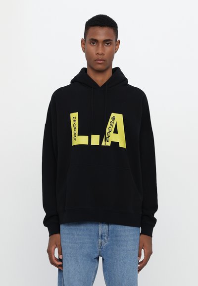 Hoodie noir avec un grand graphic "L.A." jaune sur le devant, équipé d'une poche kangourou et d'une capuche à cordon. Matière en coton doux.