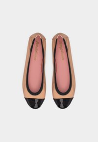 Μπεζ μπαλαρίνες με μαύρα πατινένια μέρη στα δάχτυλα, ροζ εσωτερικά πέλματα και μαύρο περιθώριο, με την ετικέτα "Pretty Ballerinas" στο εσωτερικό.
