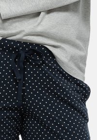 Marineblauwe sweatpants met een stippenmotief en een koord in de taille, gecombineerd met een grijze shirt met lange mouwen van zachte, lichte stof.