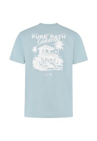 Lichtblauwe katoenen t-shirt met een witte afbeelding van een huis met palmbomen en de tekst "Pure Path Getaway" op de achterkant. Korte mouwen.