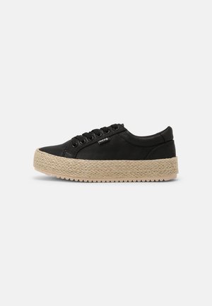 Zapatilla de lona negra con suela plataforma de yute tejido, punta redondeada y seis ojales. Presenta una etiqueta con el logo en el lateral y detalles texturizados.