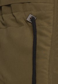 Tissu vert olive avec une surface texturée, doté d'un cordon de serrage noir et d'une quincaillerie métallique pour la fermeture.