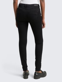 Černé skinny džíny vyrobené z denimu, s vysokým pasem, dvěma zadními kapsami a slim fit střihem. V kombinaci s černými pantoflemi.