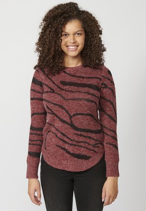 Pull rouge avec des rayures noires ondulées, manches longues, encolure ronde et tissu tricoté à texture douce, avec un ourlet légèrement arrondi.